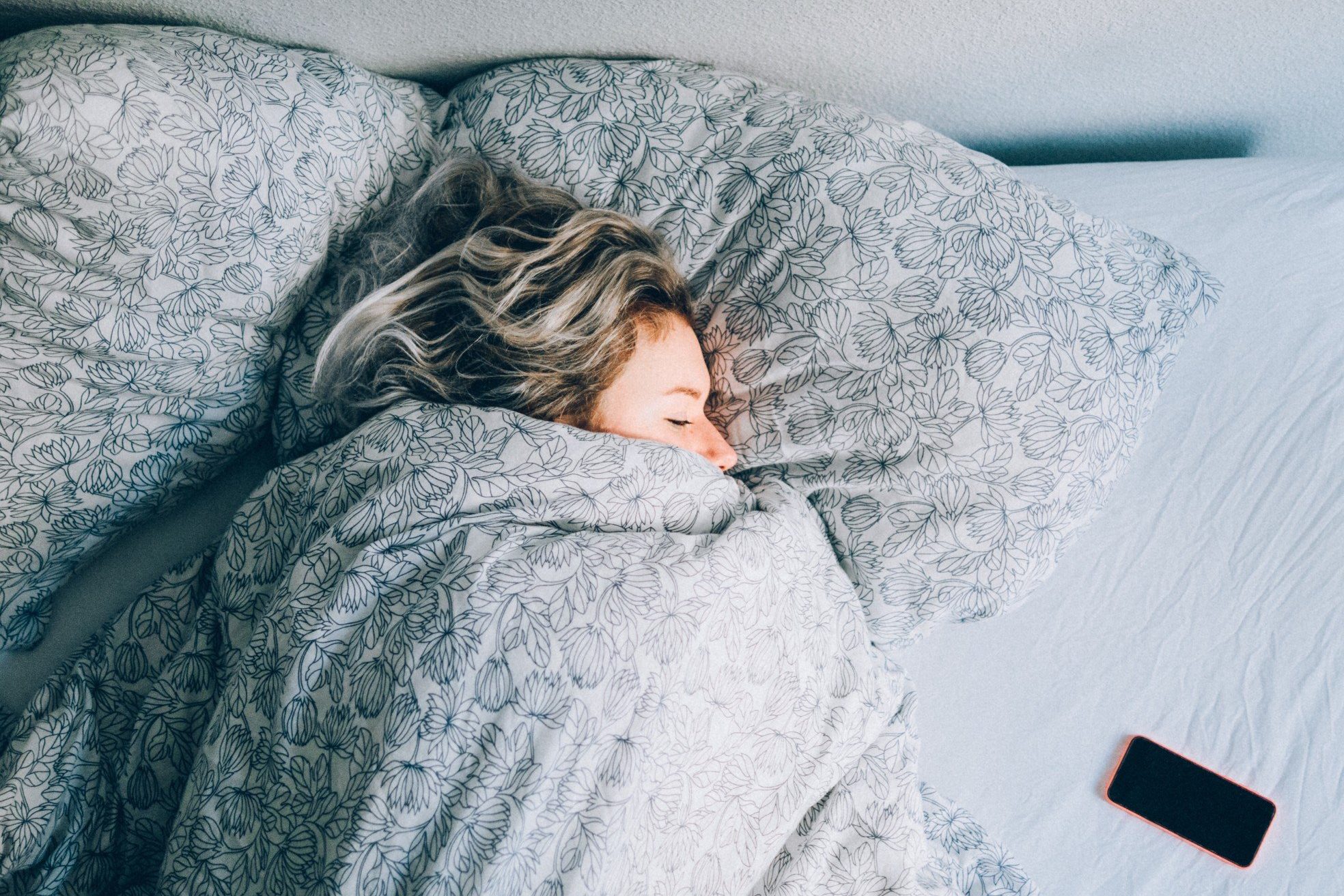 woman sleeping in bed covered by blanket