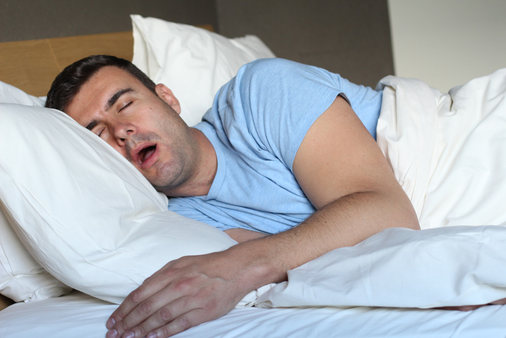 man sleeping in bed with mouth open
