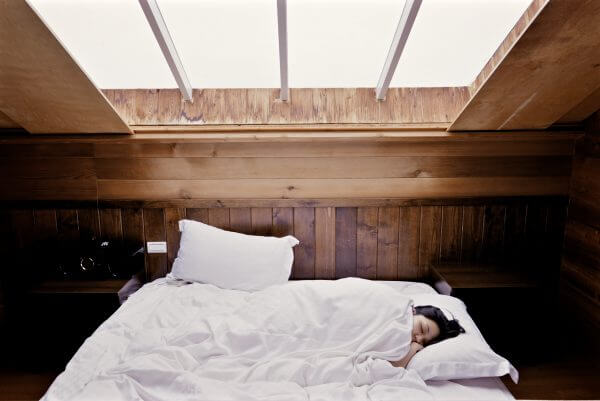 woman sleeping in bed under skylight