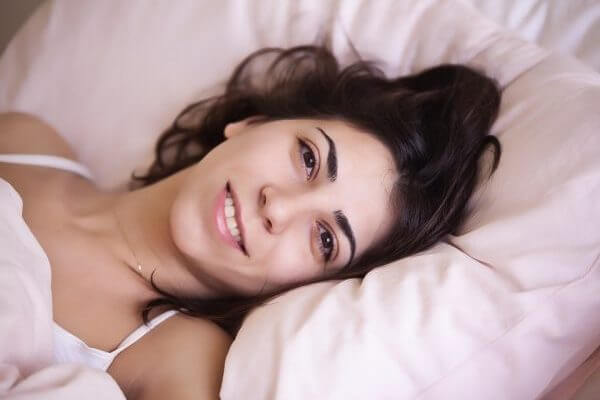 woman in bed looking at camera and smiling