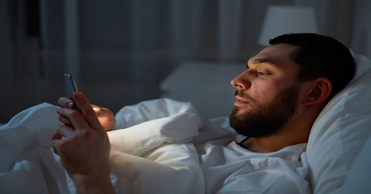 man in bed using cell phone
