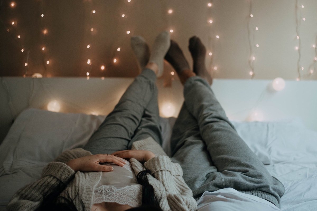 couple laying on bed with legs on the wall