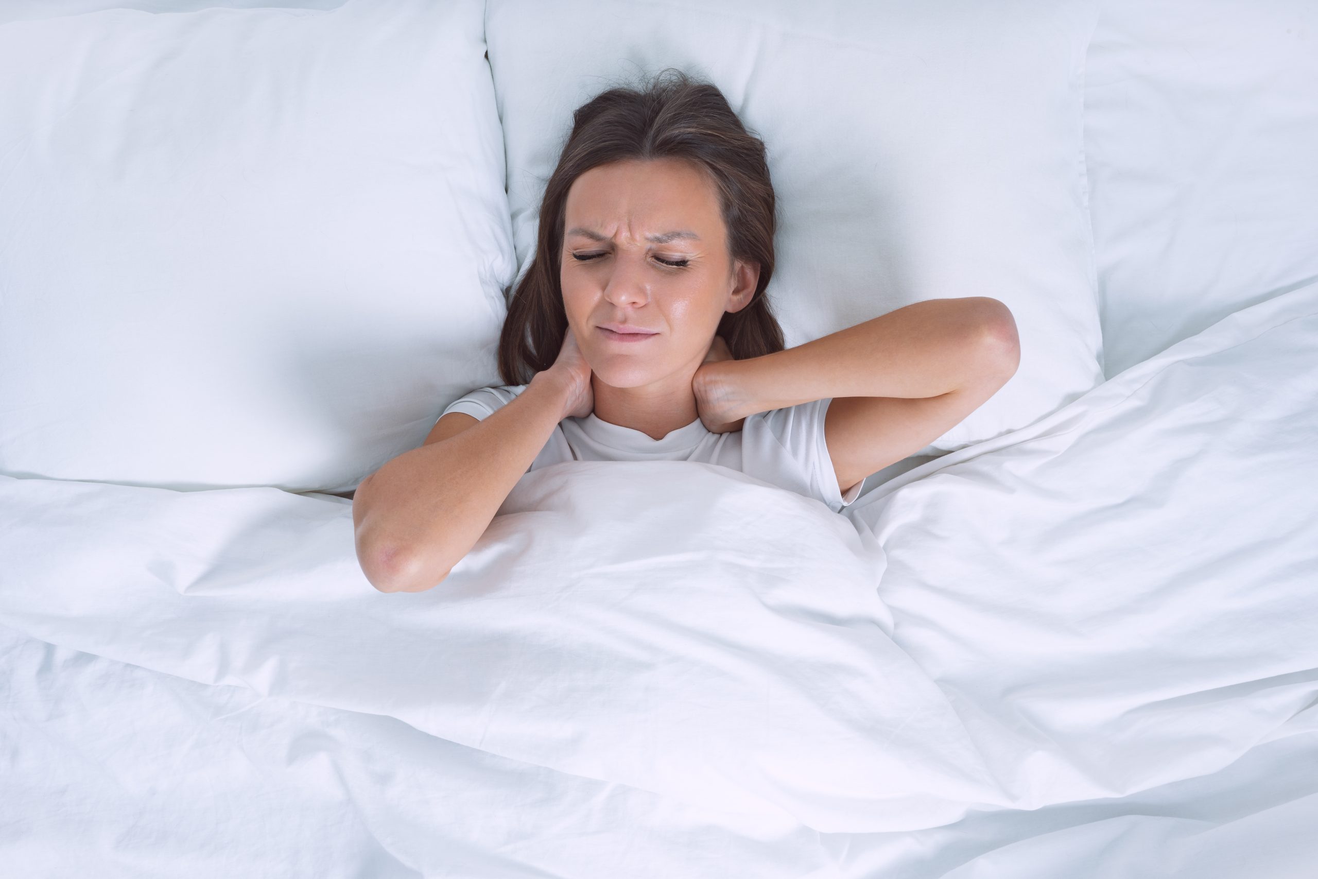 Woman in bed suffering from neck pain in the morning after sleeping