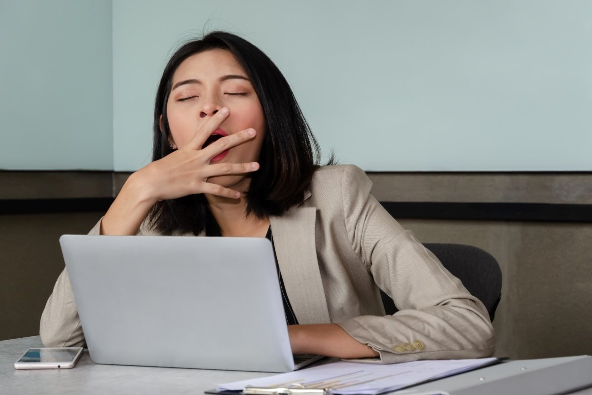 woman yawning while working at her laptop